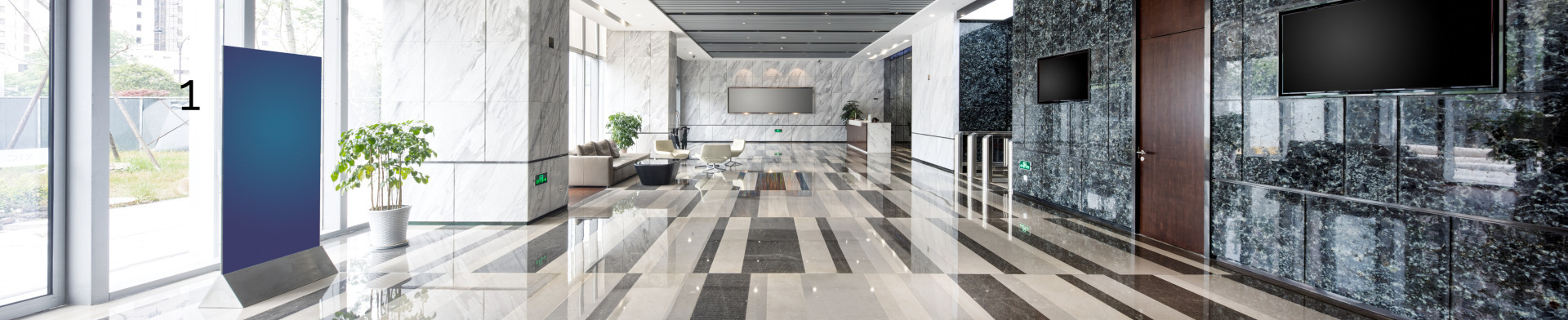 A high end building lobby with televisions on the walls and fancy flooring as well as a lounging area.