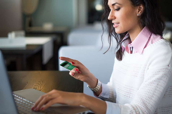 Woman at computer with credit card in hand 