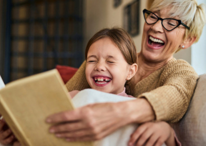 Woman and child read a book and laugh