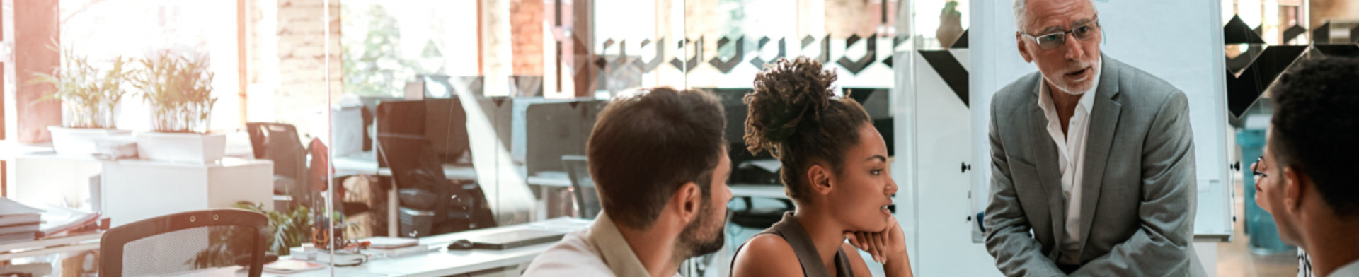 Four people discussing business in a glass conference room.