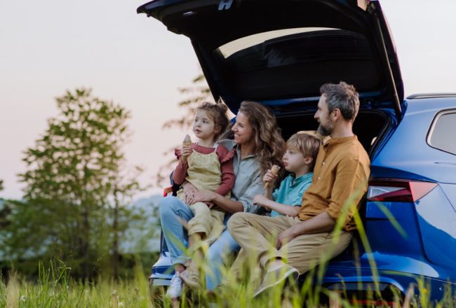 Family enjoying ice cream by their car 