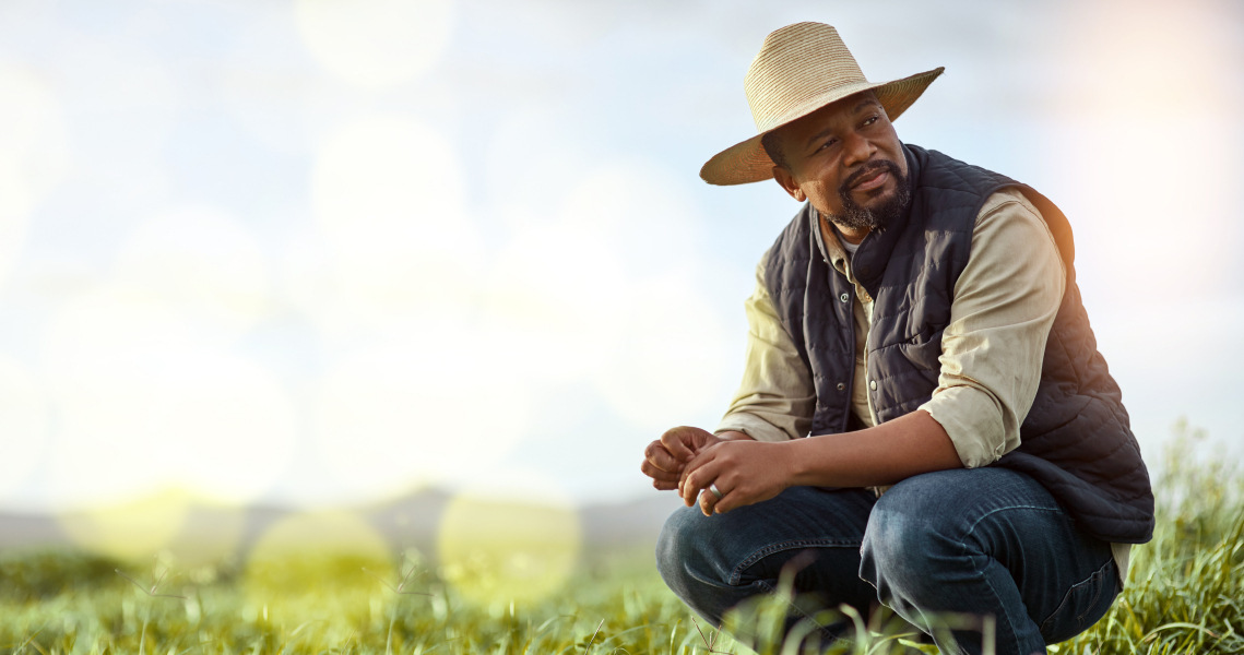 Farmer kneeling near crops
