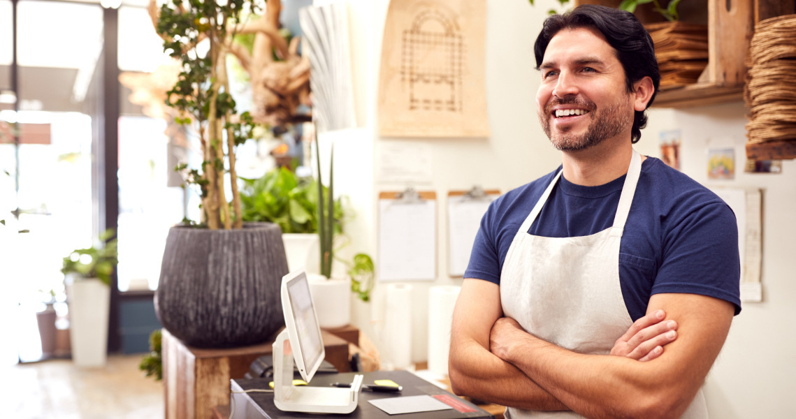 Man in apron with arms crossed smiling