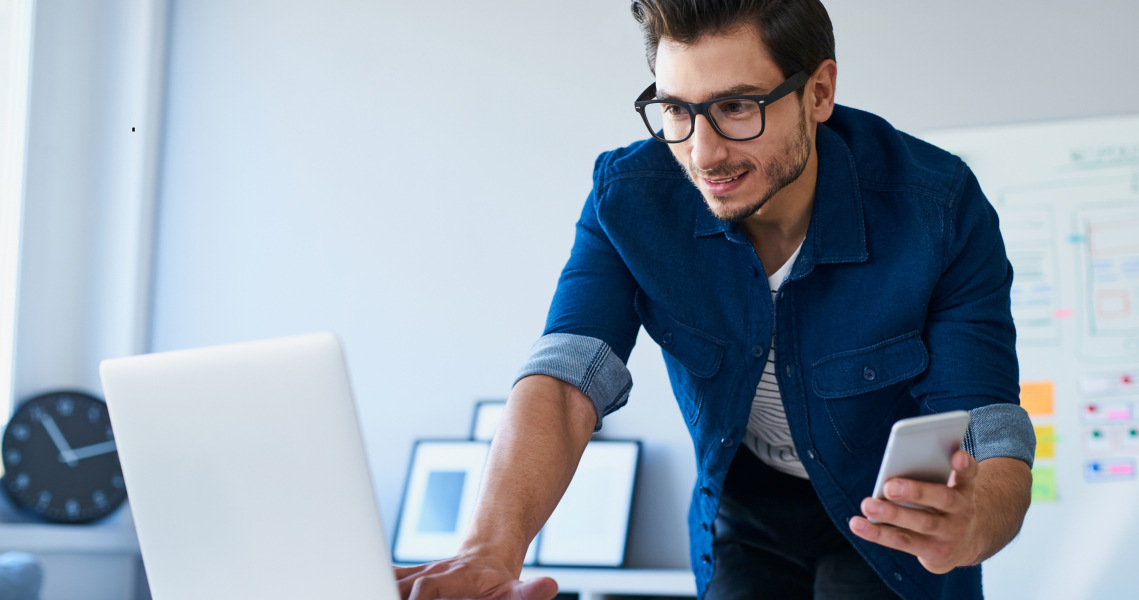 Man leaning over desk multi-tasking
