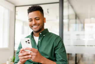 Man holding cell phone and smiling.