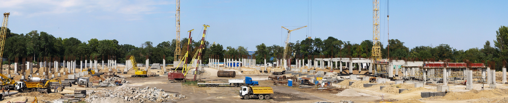 A wide angle view of a large construction site with different construction vehicles. 